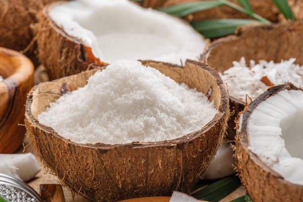 istock Fresh opened coconuts along with coconut slices, flakes and coconut leaves on a wooden table. Nice fruit background for your projects. 2106306313