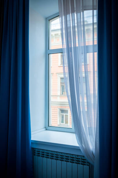 istock A window with blue curtains and a beautifully falling tulle. 2106322032