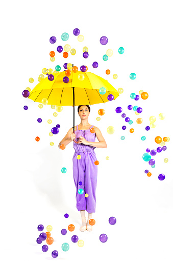 Colorful balls are raining from the sky. Beautiful ballerina is protected from colorful balls with her Japanese umbrella.