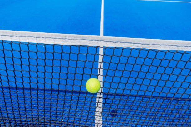 мяч для паддл-тенниса попадает в сетку синего корта для паддл-тенниса - tennis baseline fun sports and fitness стоковые фото и изображения