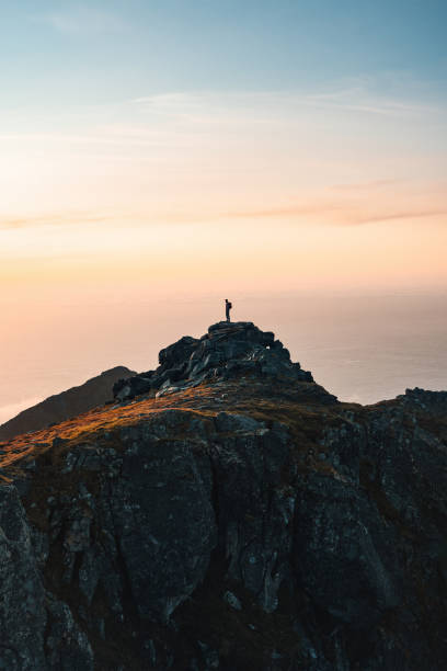 istock Man backpacker standing on mountain summit alone active travel in Norway hiking outdoor healthy lifestyle adventure vacations exploring Lofoten islands climbing expedition eco tourism 2106375442