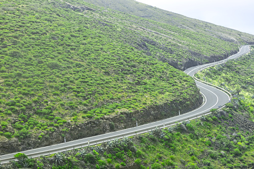 Winding road in the middle of a green hill. Serpentine asphalt road among green landscape