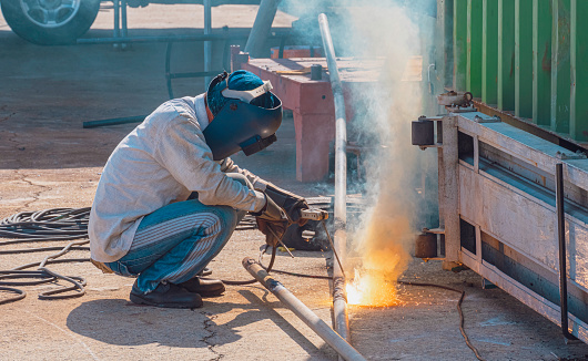 Welder with safety equipment using arc welding machine to welding steel pipe for improvement outdoor sunshade canopy structure outside of workshop