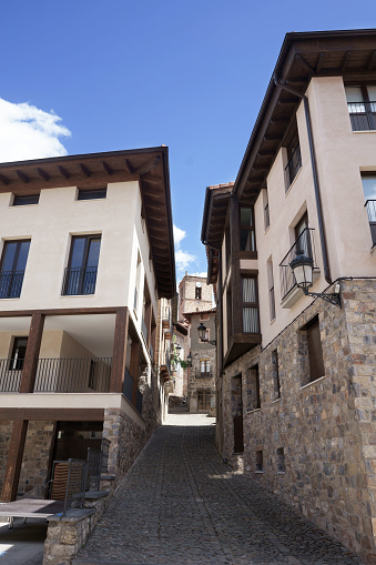 A narrow alleyway is flanked by two buildings. These structures are constructed of stone and boast a rustic charm.