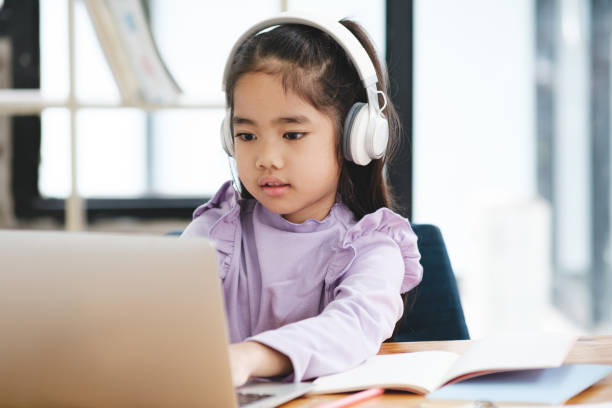 istock A young girl is sitting at a desk with a laptop and a notebook 2106444900
