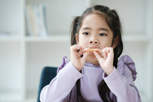 istock A young girl is eating a snack while sitting in a chair 2106444909