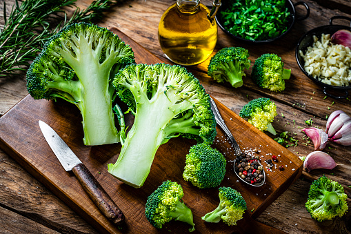 Freshly halved organic broccoli on wooden cutting board
