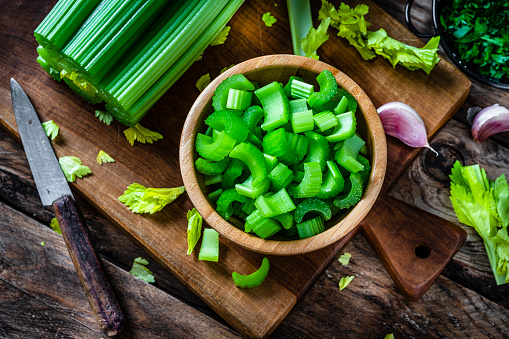 Wooden bowl filled with fresh organic chopped celery