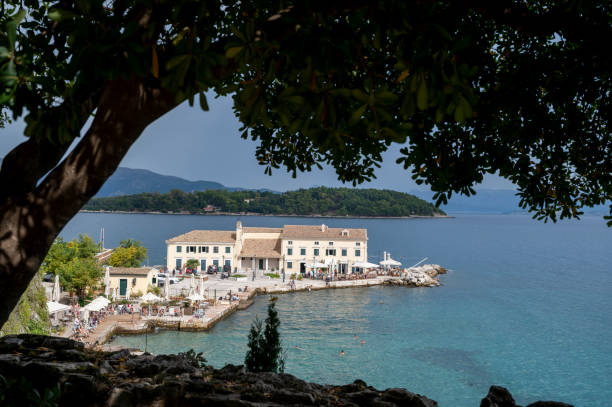 View through tree branches to calm bay and village below