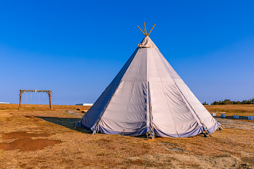 Native American tipi tent set in forest area.