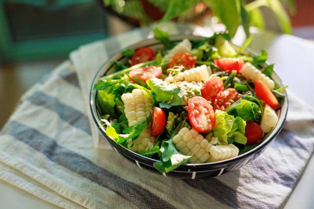 Indulge in a nutritious homemade vegetable salad, adorned with plump cherry tomatoes, sweet corn kernels, fresh rocket leaves, and a sprinkling of healthy flaxseed. Served elegantly in a bowl, it's a feast for both the eyes and the taste buds.