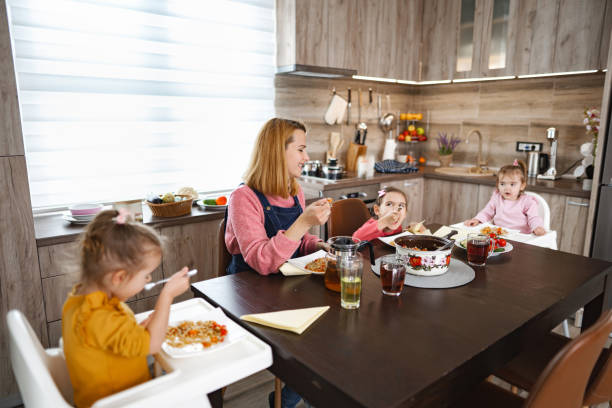 istock Caring mother enjoying eating lunch with her three daughters at home 2106633731