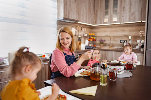 istock Caring mother enjoying eating lunch with her three daughters at home 2106648573