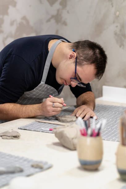 istock Young man with Down Syndrome making heart shape on clay 2106649082