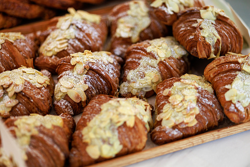 Freshly baked almond croissants display on a tray in a bakery shop