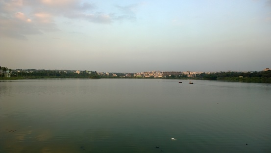 A serene view of the lake in Bengaluru with two boats and city buildings in the distance