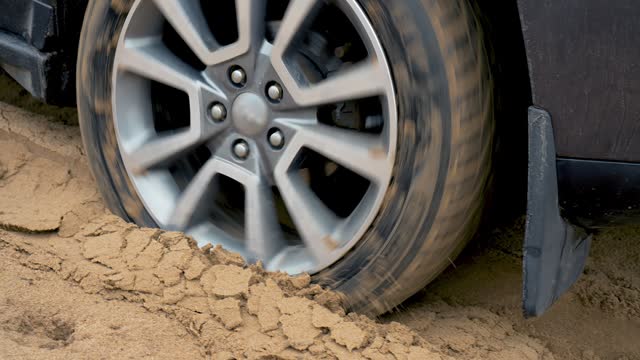 Tires close up. Powerful SUV leaves deep sand. Car glides over rough terrain. Extreme driving conditions in bad weather