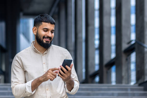 istock Smiling man using smartphone in urban setting, happy and connected 2106695402