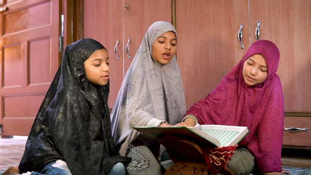 Beautiful Islamic girls sitting on met reading holy Quran in Ramadan.