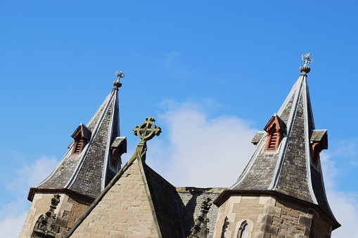 Cross and spires of Congregational Church, Panmure Street, Dundee, Scotland, against blue sky and clouds