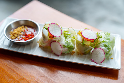 A refreshing appetizer of cut avocado, turnip, vermicelli, lettuce, mint, and bean sprouts, wrapped in a rice paper roll, served with a dipping sauce. Popular Vietnamese Fresh Vegetarian Spring Rolls