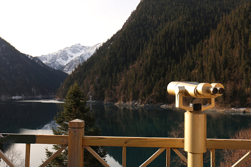 Coin-operated binoculars on the background of a mountain lake.