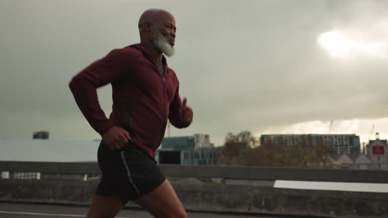 Senior African man, running and city in street, morning and vision for fitness, health and profile in retirement. Elderly runner, urban road and training with exercise, freedom or bridge in Cape Town