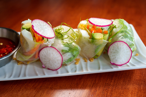 A refreshing appetizer of cut avocado, turnip, vermicelli, lettuce, mint, and bean sprouts, wrapped in a rice paper roll, served with a dipping sauce. Popular Vietnamese Fresh Vegetarian Spring Rolls