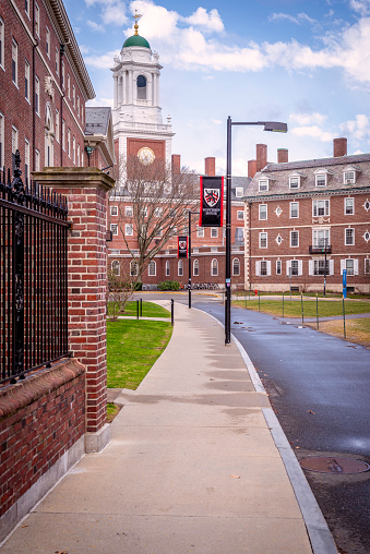 Cambridge, MA, USA - March 20, 2024: view of the iconic architecture of the famous Harvard University in Cambridge, Massachusetts, USA on a winter day with some locals and students passing by.