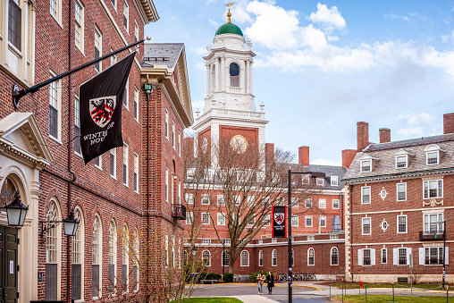 Cambridge, MA, USA - March 20, 2024: view of the iconic architecture of the famous Harvard University in Cambridge, Massachusetts, USA on a winter day with some locals and students passing by.