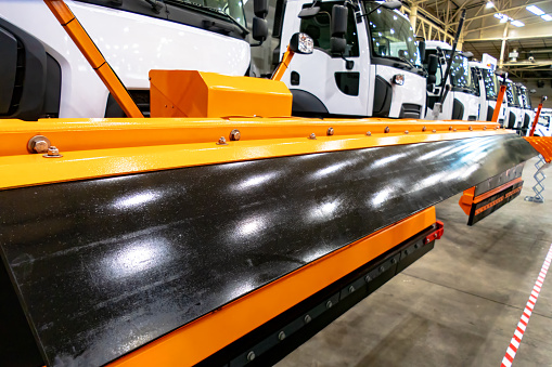 Sand and salt dispensing vehicles with a humidification system. New snowplows stand in a row