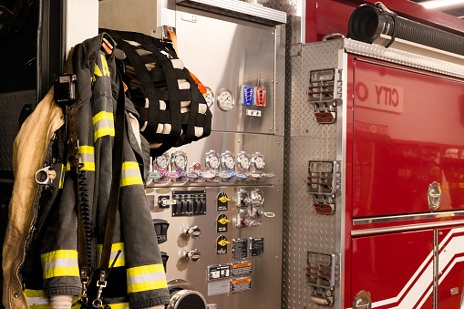 A fire jacket hangs next to an instrument panel on a fire truck in the fire station garage