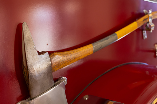 A fireman's axe is mounted on the side of a red fire truck