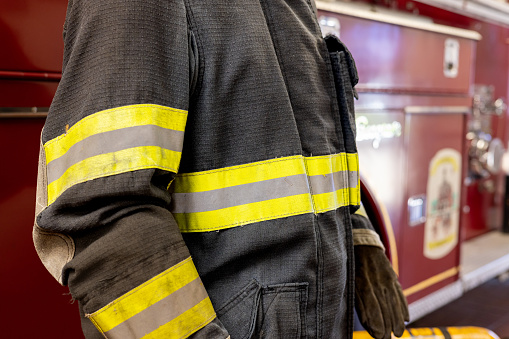 A fireman stands in front of a fire truck in a garage