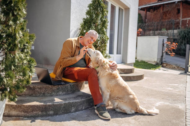 istock Man working on laptop and playing with his dog in back yard 2106785365