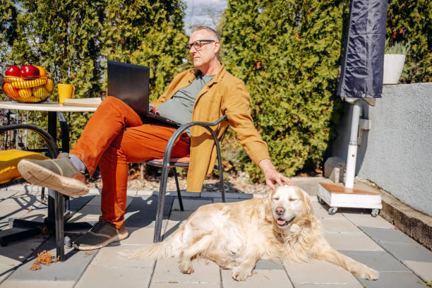istock Man playing with his dog in back yard while working on laptop 2106785387