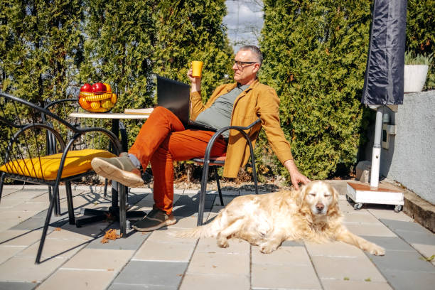 istock Man playing with his dog in back yard while working on laptop 2106786401