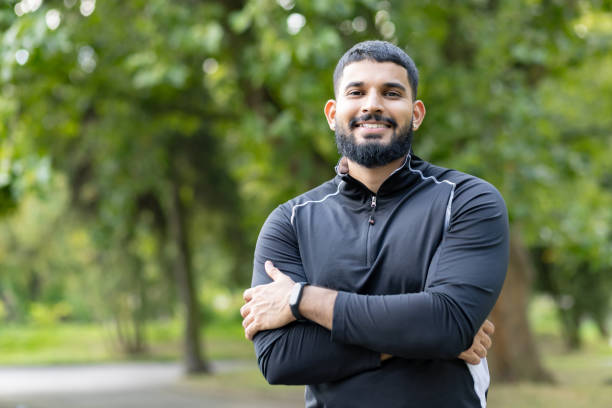istock Confident man standing with arms crossed in a park 2106855106