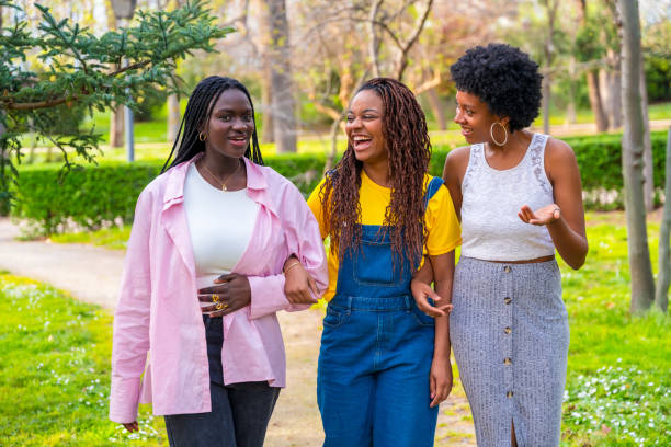 istock African friends walking arms to arm along a park path 2106867818