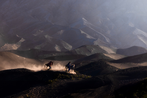 Volcanic riders on horseback gallops across the sands at Mount Bromo.\nMount Bromo,Probolinggo, East Java, Indonesia - July 28 2023 : the riders on horseback gallops across the sands at Mount Bromo to provide services for tourist who want to visit., the spectacular volcanic peak that is situated high up in the Tengger mountains on the Indonesian island of Java,Indonesia.