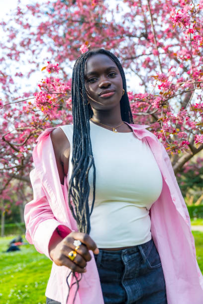 istock African woman posing next to flowering pink tree 2106868114