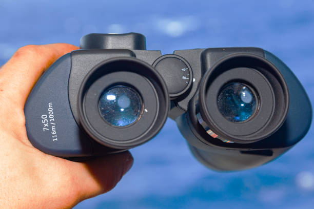 istock Male hand hold optical binoculars towards the sea. 2106870834