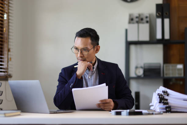 istock Serious executive businessman is busy with paperwork on the table in the office. 2106874598