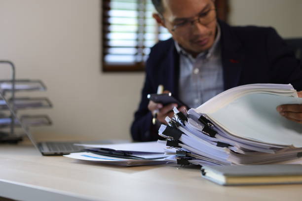istock Serious executive businessman is busy with paperwork on the table in the office. 2106875673