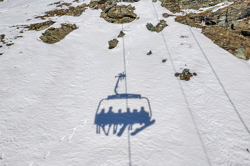 Shadow of family on ski lift at Swiss ski resort on a sunny winter day