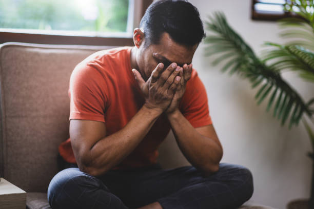 istock A man sitting on a sofa at home is sad, disappointed and upset. 2106879354