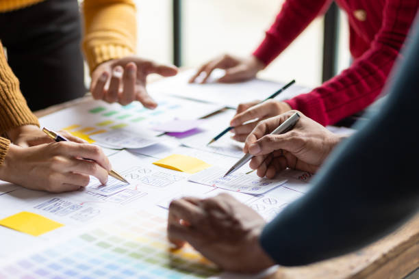 istock UX, UI designers collaborate to design user interfaces for smartphone apps based on user experience. Colleagues meeting, program designers brainstorm to discuss designing mobile applications. 2106881528