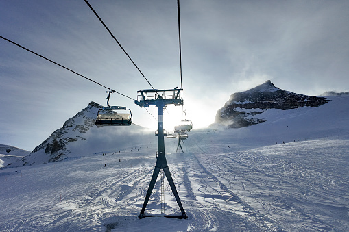 Backlit snowcapped mountains and chairlift, Swiss Alps