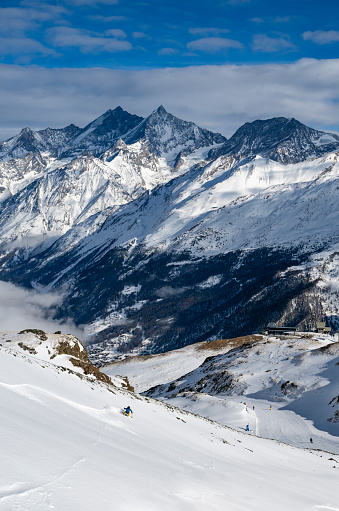 Woman skis at down slope at Swiss ski resort on a sunny winter day