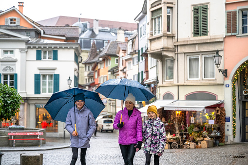 Family explores old town under umbrellas on a rainy day